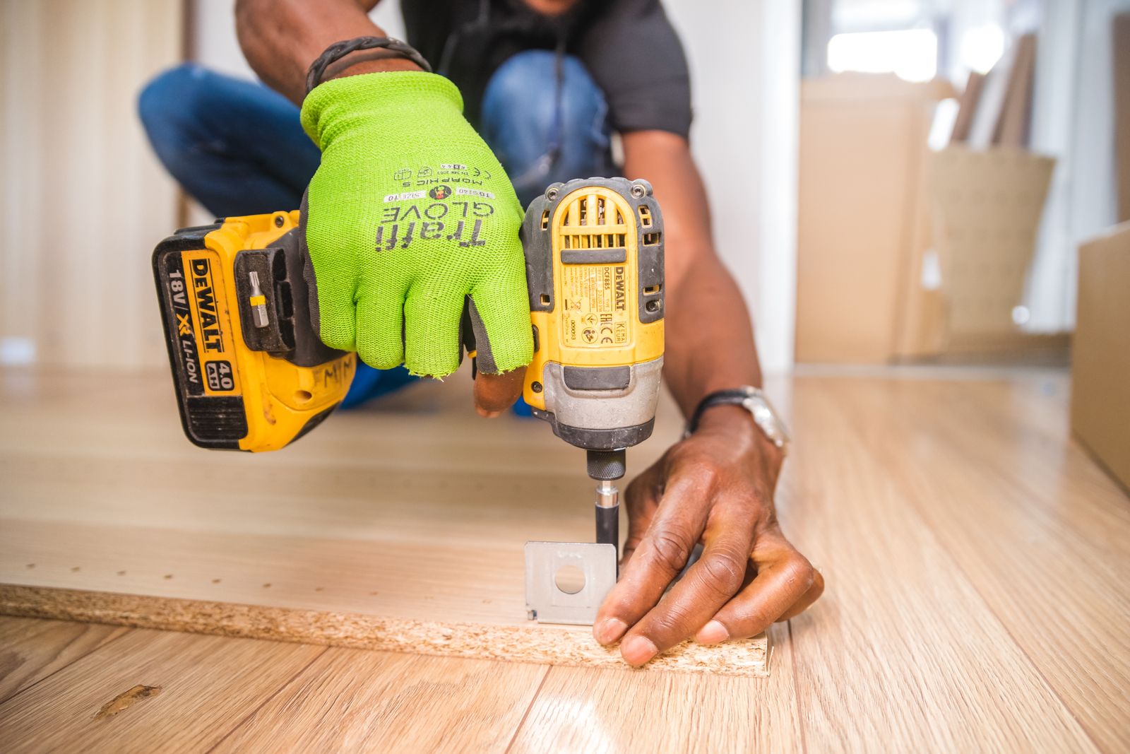 Gloved hands driving a screw with a cordless drill while mounting hardware